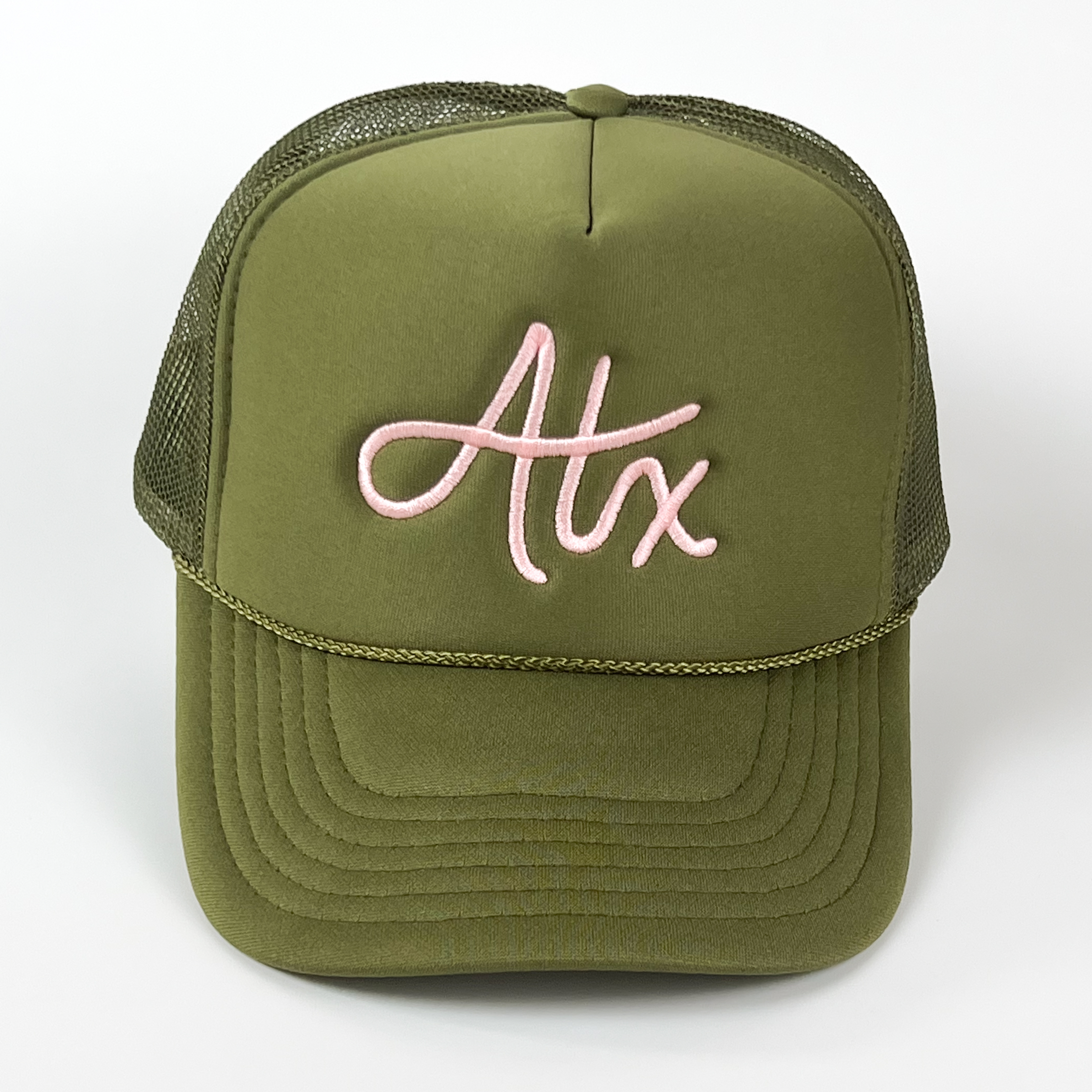 A olive green trucker cap with 'ATX' embroidered in a light pink thread.
