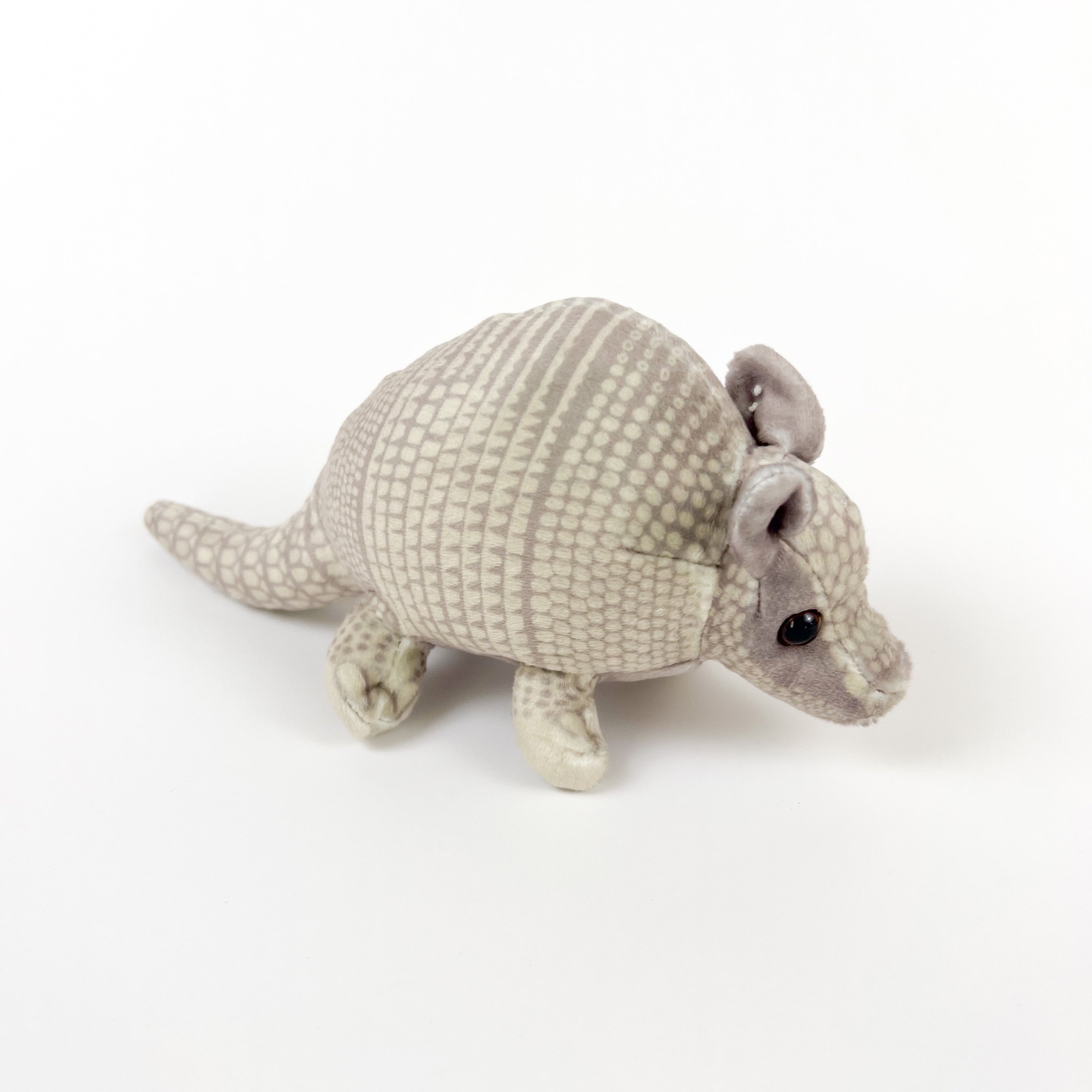 A plush toy resembling a small grey armadillo with a soft texture, made from recycled plastic.