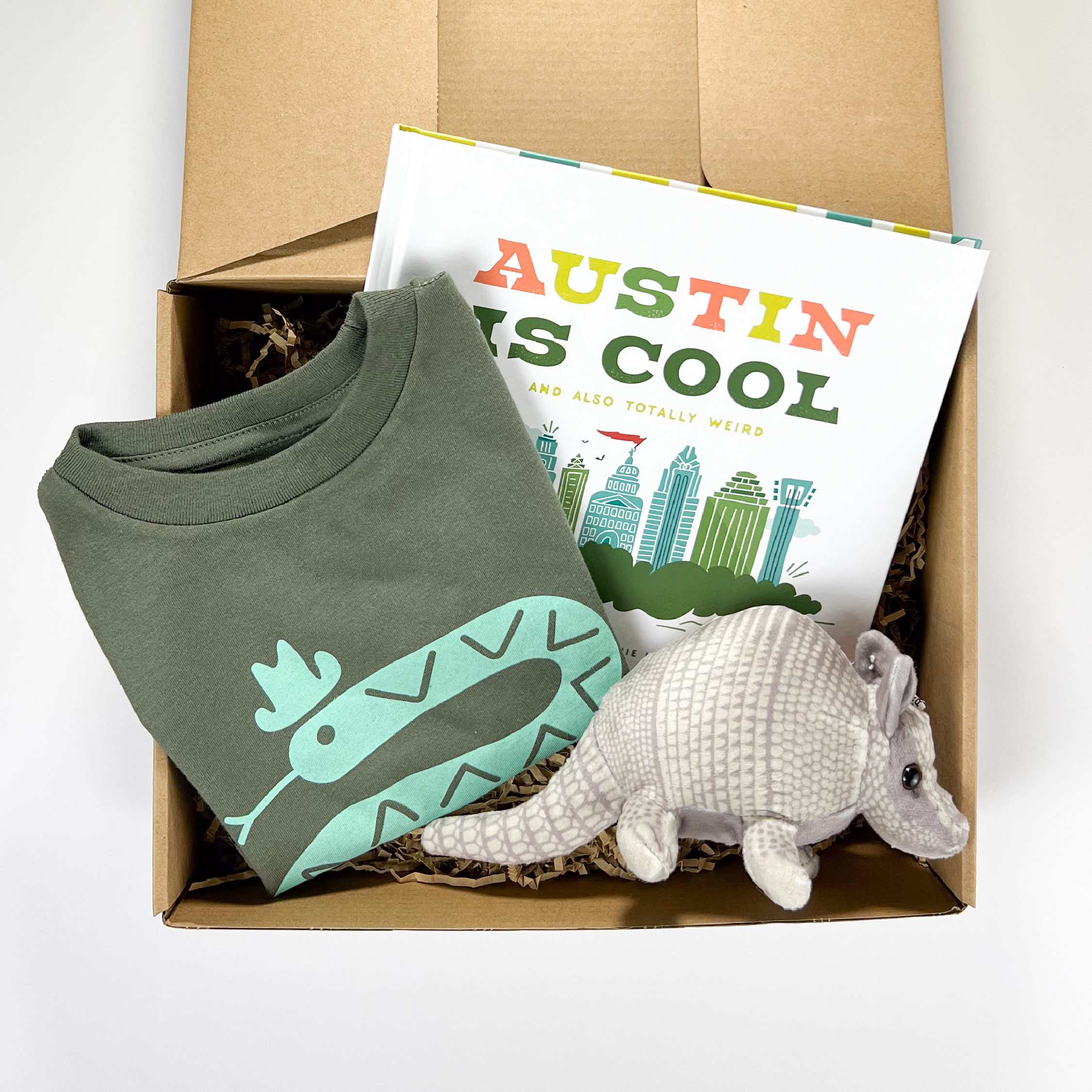 An Austin gift box for children that includes a book, tshirt, and armadillo stuffed animal.